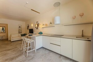 A modern kitchen with a central island, white cabinetry, and pendant lighting.