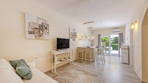 Un saló modern amb un sofà, televisió i obres d'art, connectat a una cuina i zona de menjador amb vistes.