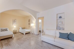 Ein Hotelzimmer mit Bett, Sofa, Lampe, Uhr und einem Regal mit Dekoration.
