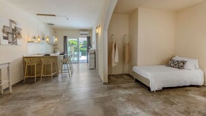 Habitació d'hotel moderna amb un llit, una cuineta petita i una zona de menjador amb cadires.