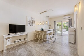 A modern kitchen with a TV, bar stools, and a dining area with a table and chairs.