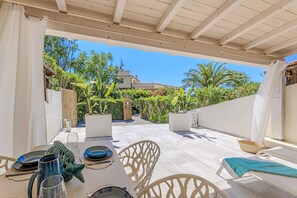 Eine Terrasse im Freien mit Esstisch, Stühlen und einer Lounge-Ecke mit einer Bank.