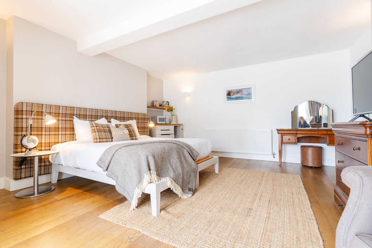A bedroom with a bed, bedside table, lamp, dresser, and a radiator.