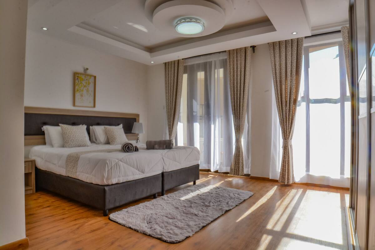 Un dormitorio moderno con una cama grande, una mesita de noche y un ventanal con cortinas.