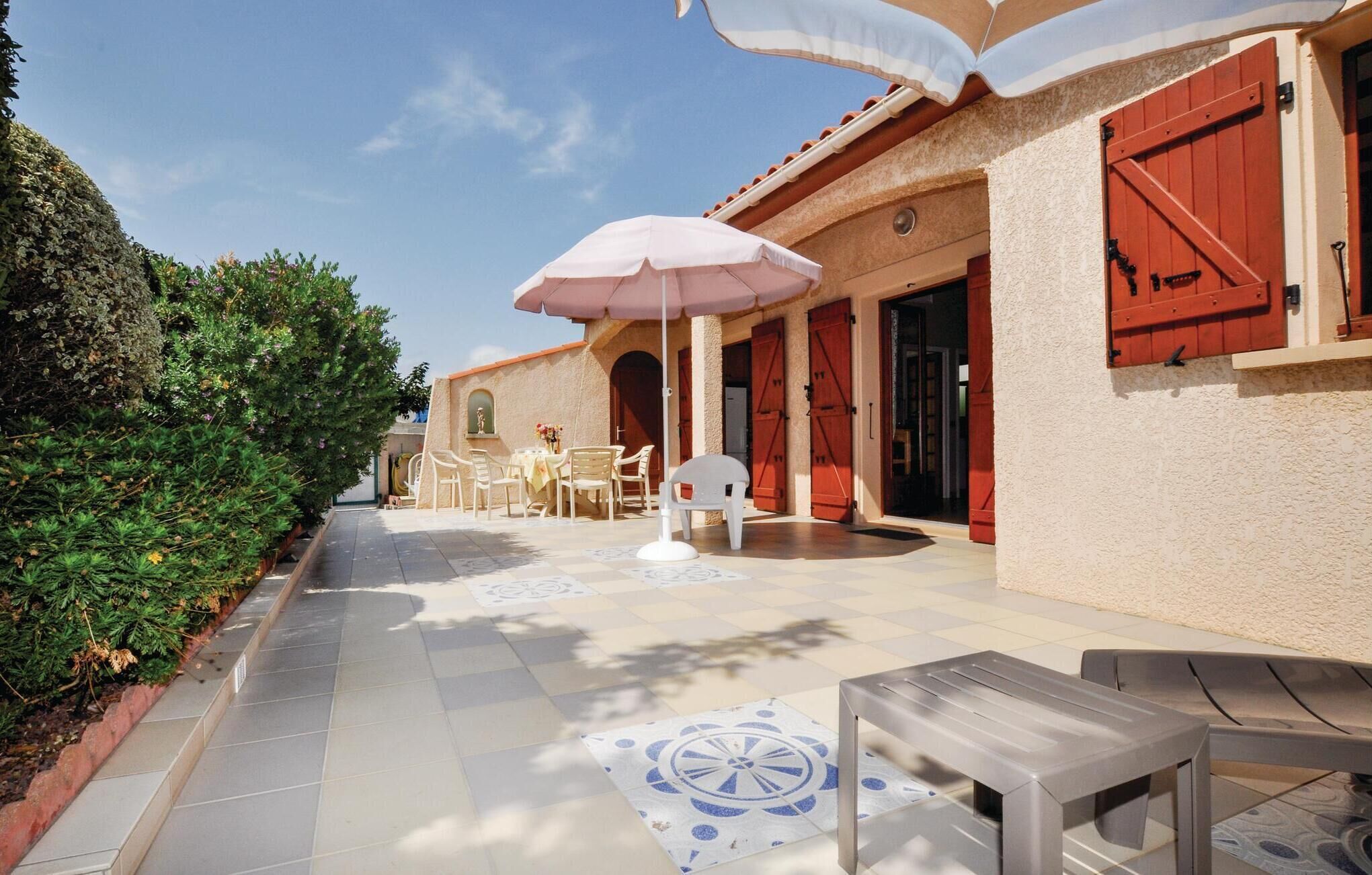 A patio with outdoor seating, a tiled floor, and a building with red shutters.