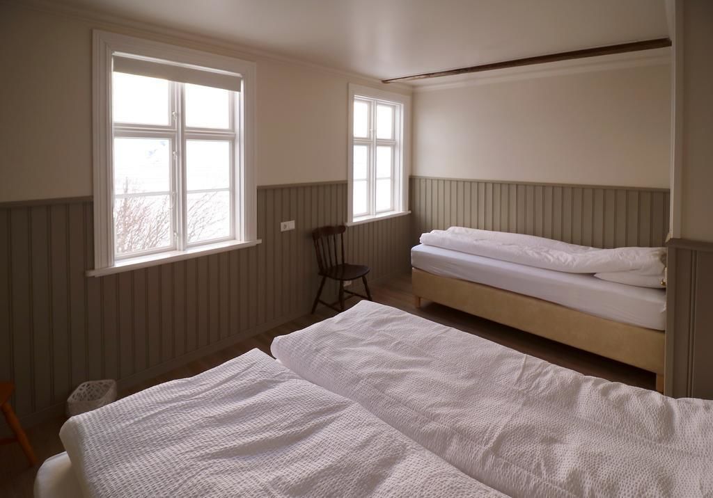 A room with two beds, a chair, and two windows.