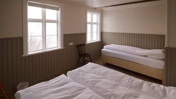 A room with two beds, a chair, and two windows.