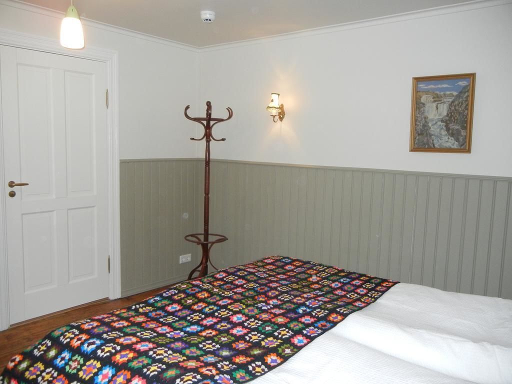 Un dormitorio con cama, perchero, luz empotrada en la pared y un cuadro.