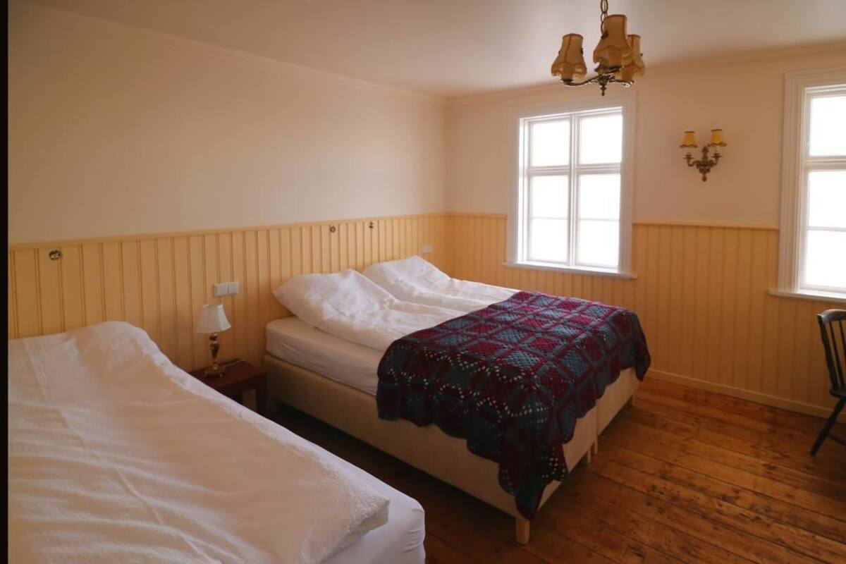 A room with two single beds, a window with a view, and a chandelier.