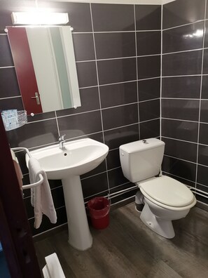 Un bagno con un lavandino bianco, un water e uno specchio sopra il lavandino.