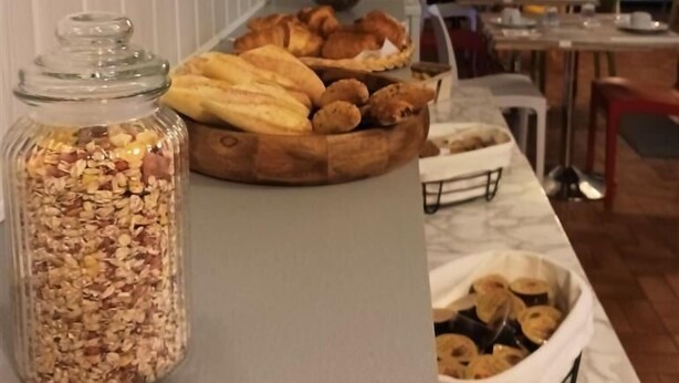 Un buffet de petit-déjeuner avec un assortiment de viennoiseries et un bocal de granola.