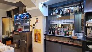 Un espace bar avec des étagères remplies de bouteilles d’alcool, de verres et une machine à café.