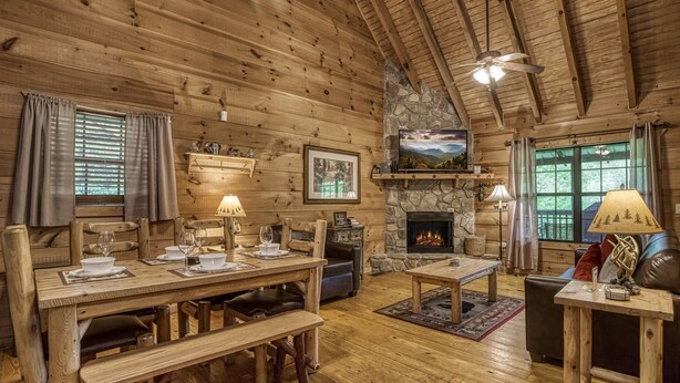 Un acogedor interior de cabaña de madera con comedor, chimenea y asientos cómodos.