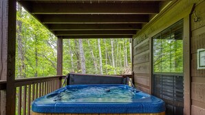 Un jacuzzi en una terraza de madera con vista a un bosque.