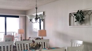 A dining area with white chairs, a granite countertop, and a chandelier.
