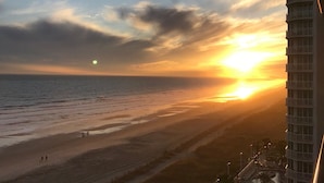 A sunset over a beach with a view of a high-rise building.