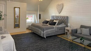 A bedroom with a large bed, a sofa, a coffee table, a mirror, and a chandelier. - Bashults Gård (Jonkoping)
