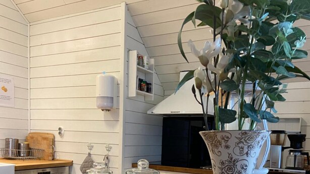 A kitchen with wooden cabinets, a microwave, a wooden countertop, a vase with flowers, and two jars of preserves. - Bashults Gård (Jonkoping)