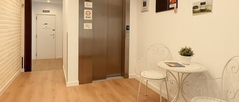 A modern interior with a wooden floor, an elevator, and a small table with chairs.