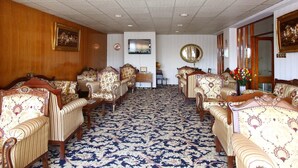 A room with a patterned carpet, wooden panel walls, and multiple upholstered chairs with ornate designs. - Guleryuz Otel (Ankara)