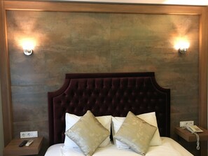 A hotel room with a tufted headboard, two bedside lamps, a bedside phone, and a nightstand with a remote control. - Guleryuz Otel (Ankara)