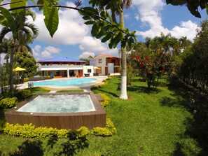 A pool area with a hot tub, lounge chairs, and a building with a red roof. - Finca Hotel La Manuela (Montenegro)