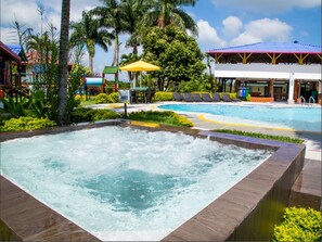 A hot tub area with a pool and lounge chairs, surrounded by palm trees and a covered pavilion. - Finca Hotel La Manuela (Montenegro)