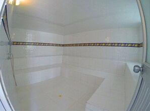 A bathroom with white tiles, a shower, and a door with a round handle. - Finca Hotel La Manuela (Montenegro)
