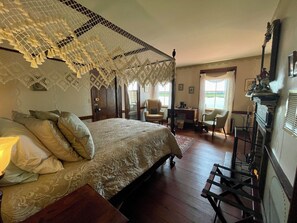 Un dormitorio tradicional con cama a laqueada, un escritorio y una chimenea.