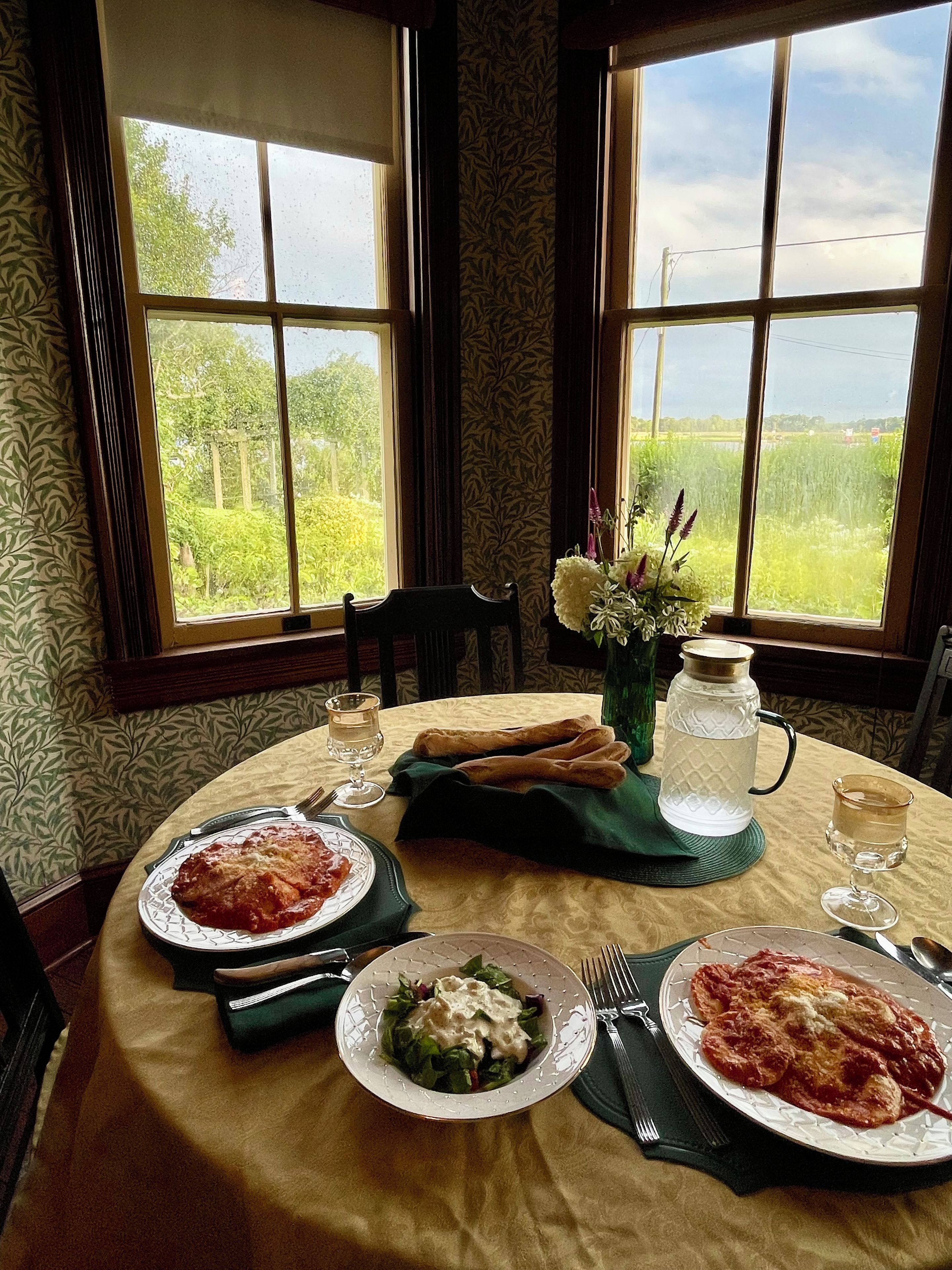 A dining table with plates of food, a pitcher, and a vase with flowers.