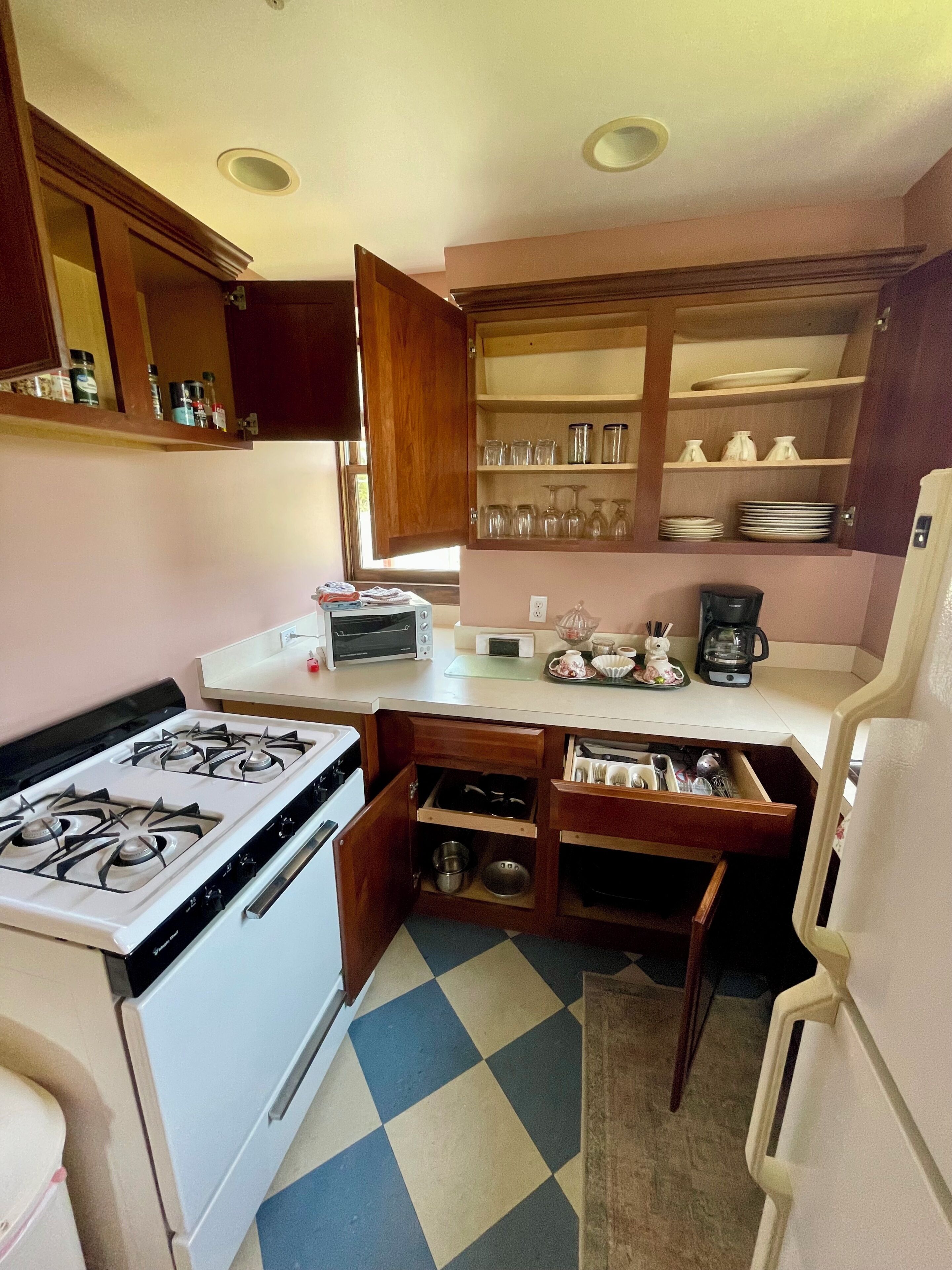 A compact kitchen with a gas stove, microwave, toaster, and a coffee maker.