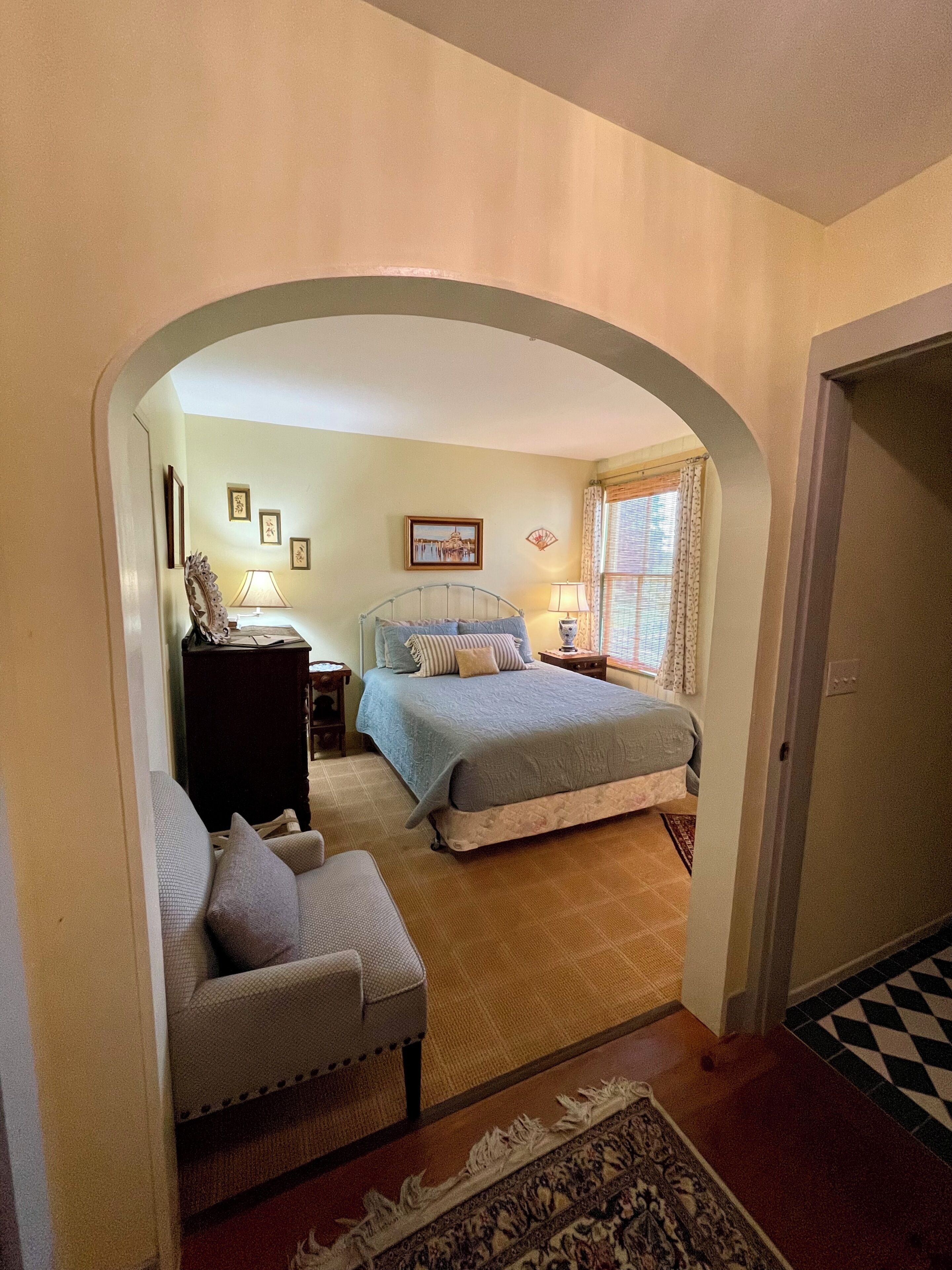 A bedroom with two beds, a dresser, a chair, and a rug.