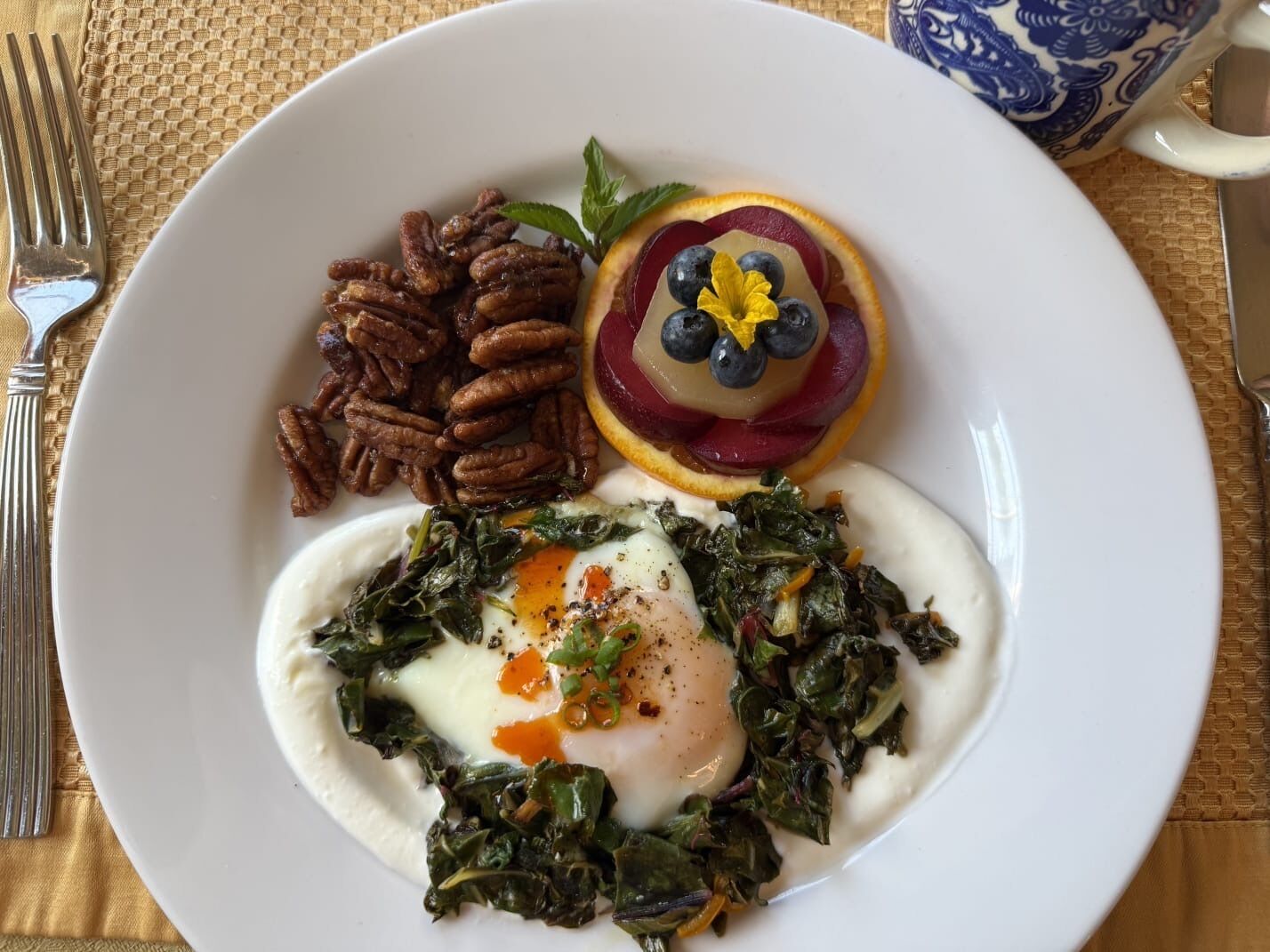 A plate with spinach, eggs, pecans, and a fruit garnish.