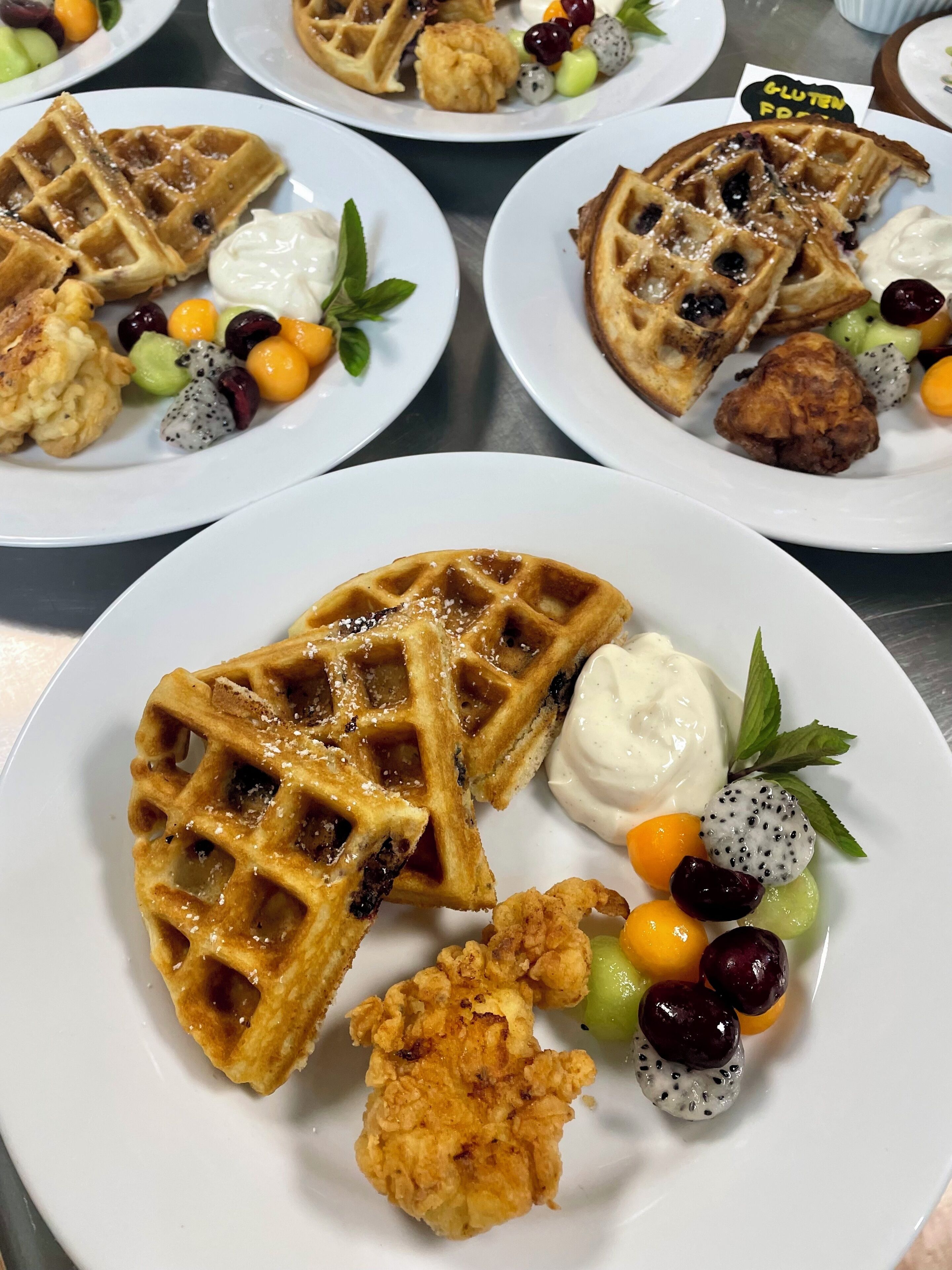 A plate with waffles, fruit, and a fried item.