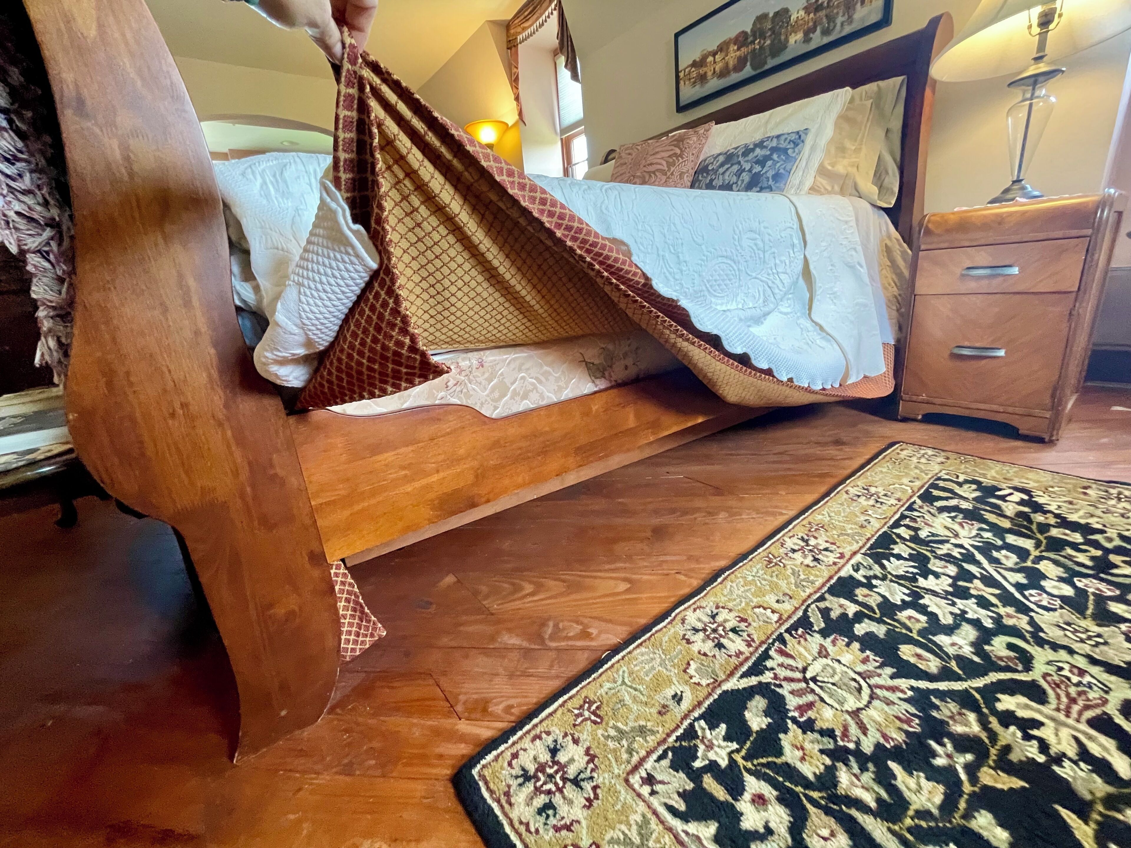 Una cama de madera con dosel, una mesita de noche y un tapete estampado.