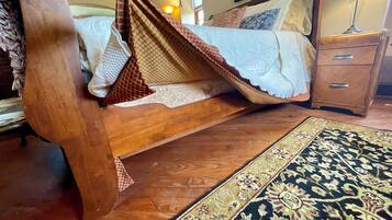 Una cama de madera con dosel, una mesita de noche y un tapete estampado.