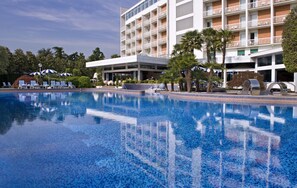Relax by the pool surrounded by lush greenery and comfortable lounge chairs.