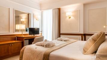 Une chambre d’hôtel avec un lit, un bureau, une télévision et un miroir.
