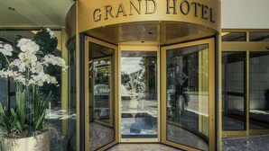 Der Eingang des Grand Hotels mit einer Doppeltür, Pflanzkübeln und einem Marmorboden.
