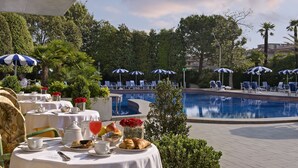 Ein Essbereich am Pool mit gedeckten Tischen, mit Blick auf einen Swimmingpool.