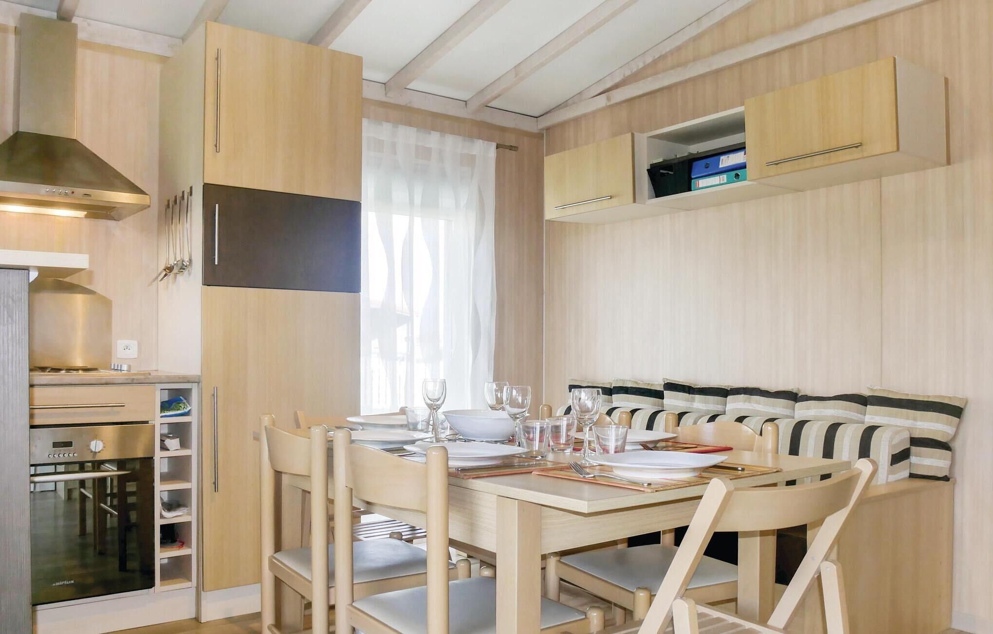 Una cucina compatta con forno a incasso, un tavolo da pranzo per quattro persone e un piccolo mobiletto sopra il tavolo.