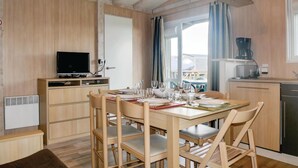 Un espacio habitable compacto con comedor, kitchenette y televisor.