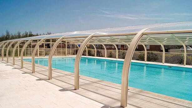 Una piscina con un deck de baldosas relucientes y una serie de pasarelas cubiertas.