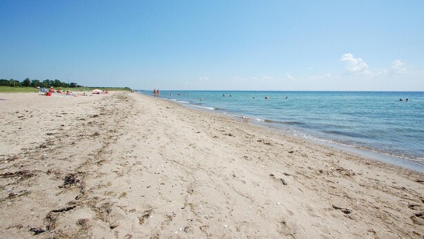 A wide sandy beach with footprints and a few people in the water. - 3 bedroom amazing home in Haderslev (Haderslev)
