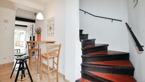 A staircase with black and red steps leading to a landing, a wooden dining table with chairs, and a hanging pendant light. - Gorgeous home in CERET with house a mountain view (CERET)