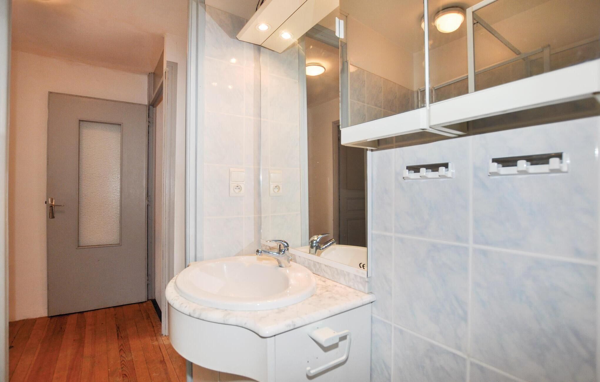 A modern bathroom with a white sink, a mirror, and a door.