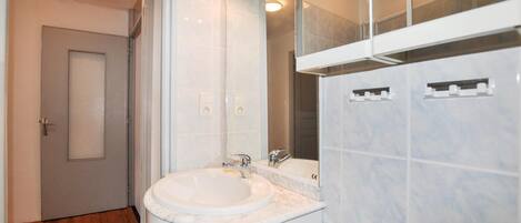 A modern bathroom with a white sink, a mirror, and a door.