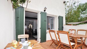 A patio with a wooden table and chairs, a green door leading to an interior space, and a hanging light fixture. - Gorgeous home in CERET with house a mountain view (CERET)
