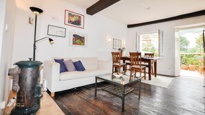 A living room with a white sofa, a coffee table, and a dining area with wooden chairs and a table. There are framed artworks on the walls and a large window providing a view of the outdoors. - Gorgeous home in CERET with house a mountain view (CERET)