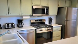 Una cucina con piano cottura in acciaio inossidabile, forno a microonde e frigorifero.